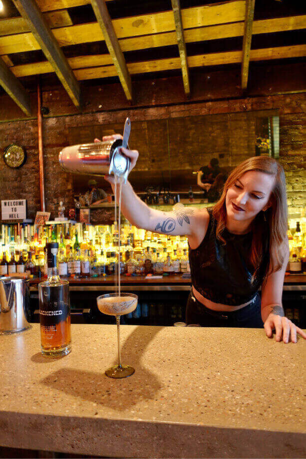 Mixologist Katie Renshaw pouring a BLACKENED cocktail in a glass