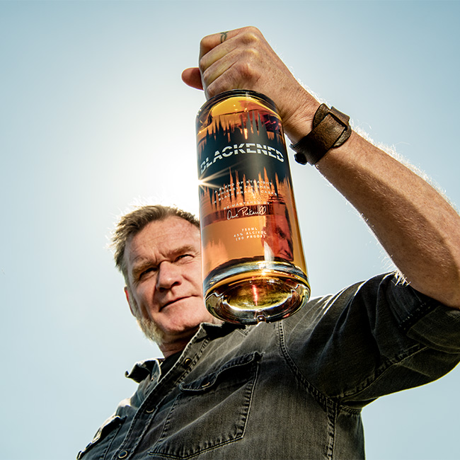 Master Distiller & Blender Rob Dietrich holding a bottle of BLACKENED American Whiskey outside