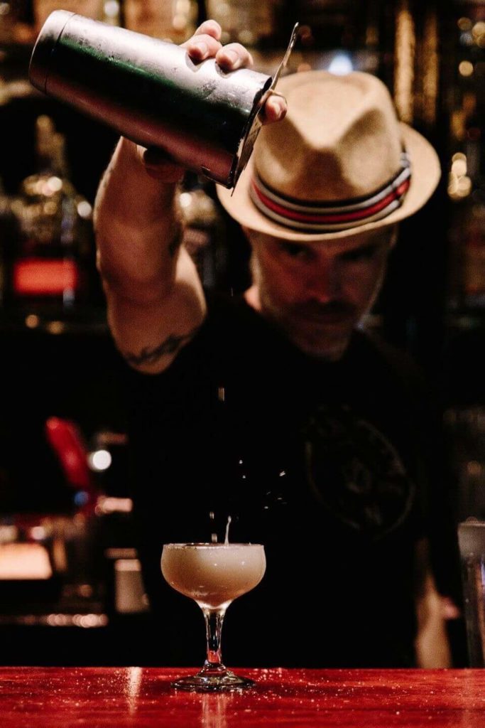 Micheal Nef pouring a cocktail in a glass